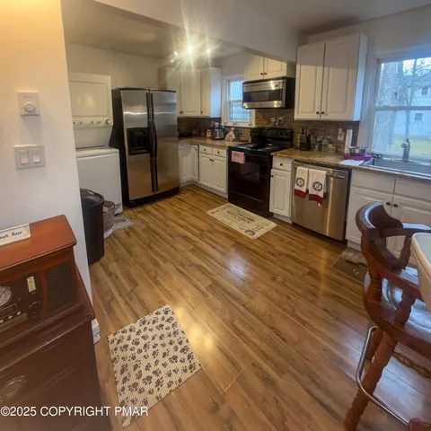 a kitchen with stainless steel appliances kitchen island granite countertop a sink dishwasher a stove and a refrigerator with wooden floor