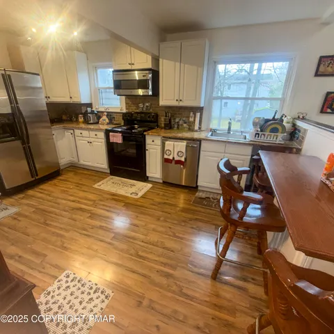 a kitchen with kitchen island a stove a sink a dining table and chairs