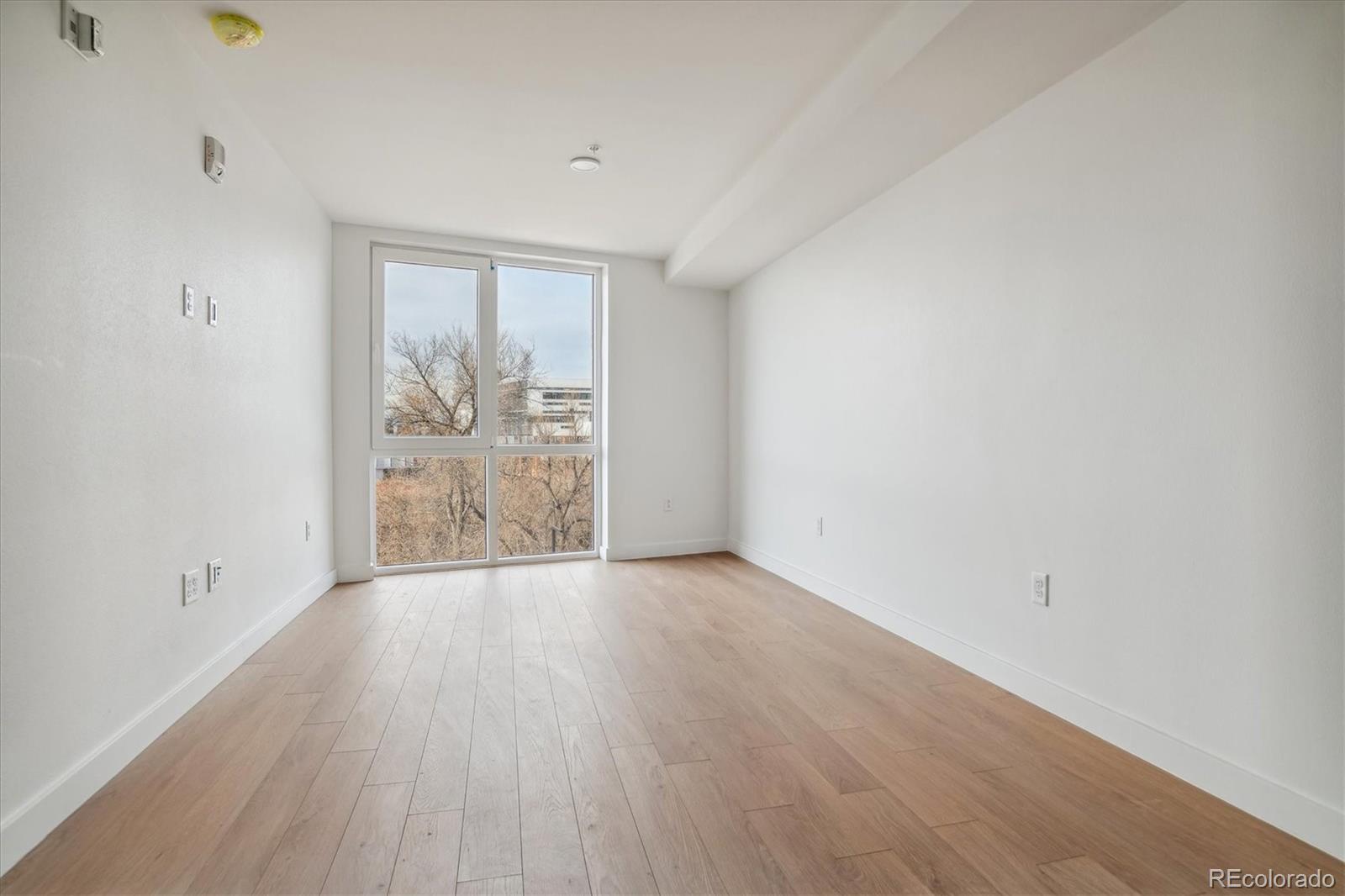3575 Chestnut Place, Unit 203 Denver, CO 80216 - Photo 7 of 14 a view of an empty room with wooden floor and a window