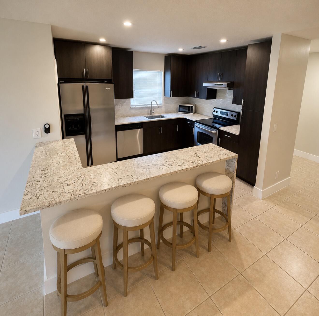 22324 Southwest 57th Circle Boca Raton, FL 33428 - Photo 2 of 22 a kitchen with stainless steel appliances a dining table chairs refrigerator and sink