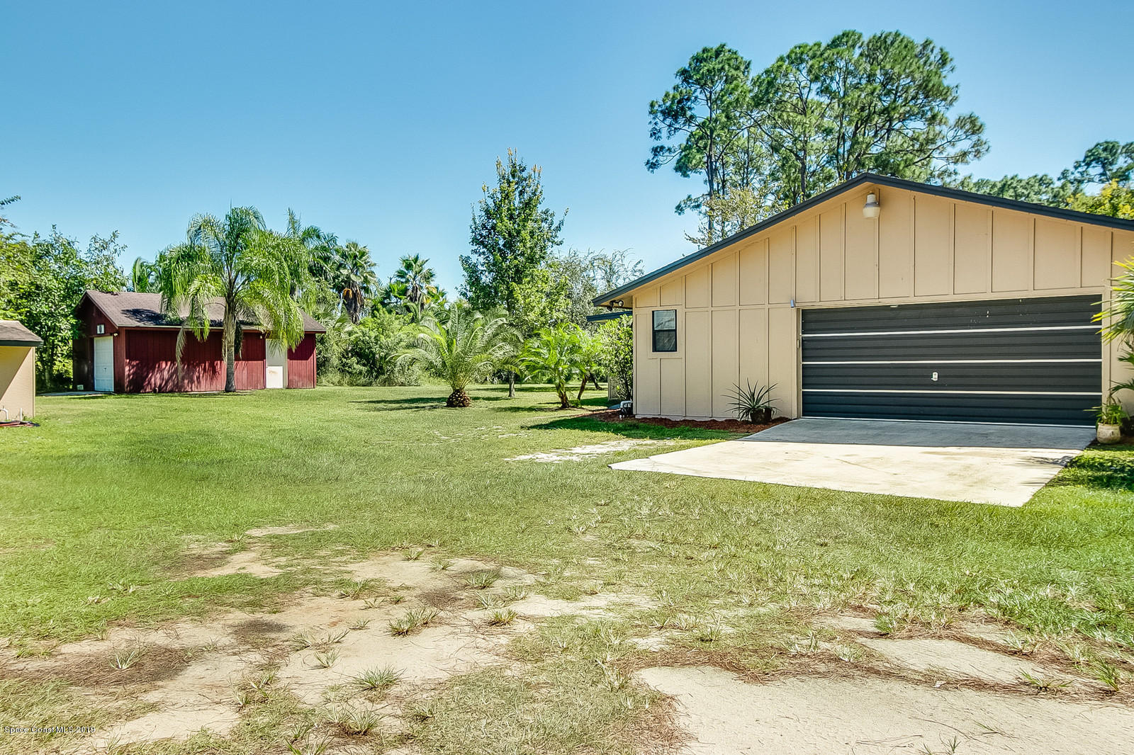 1695 Emmaus Road Northwest Palm Bay, FL 32907 - Photo 27 of 30 a backyard of a house with large trees and plants