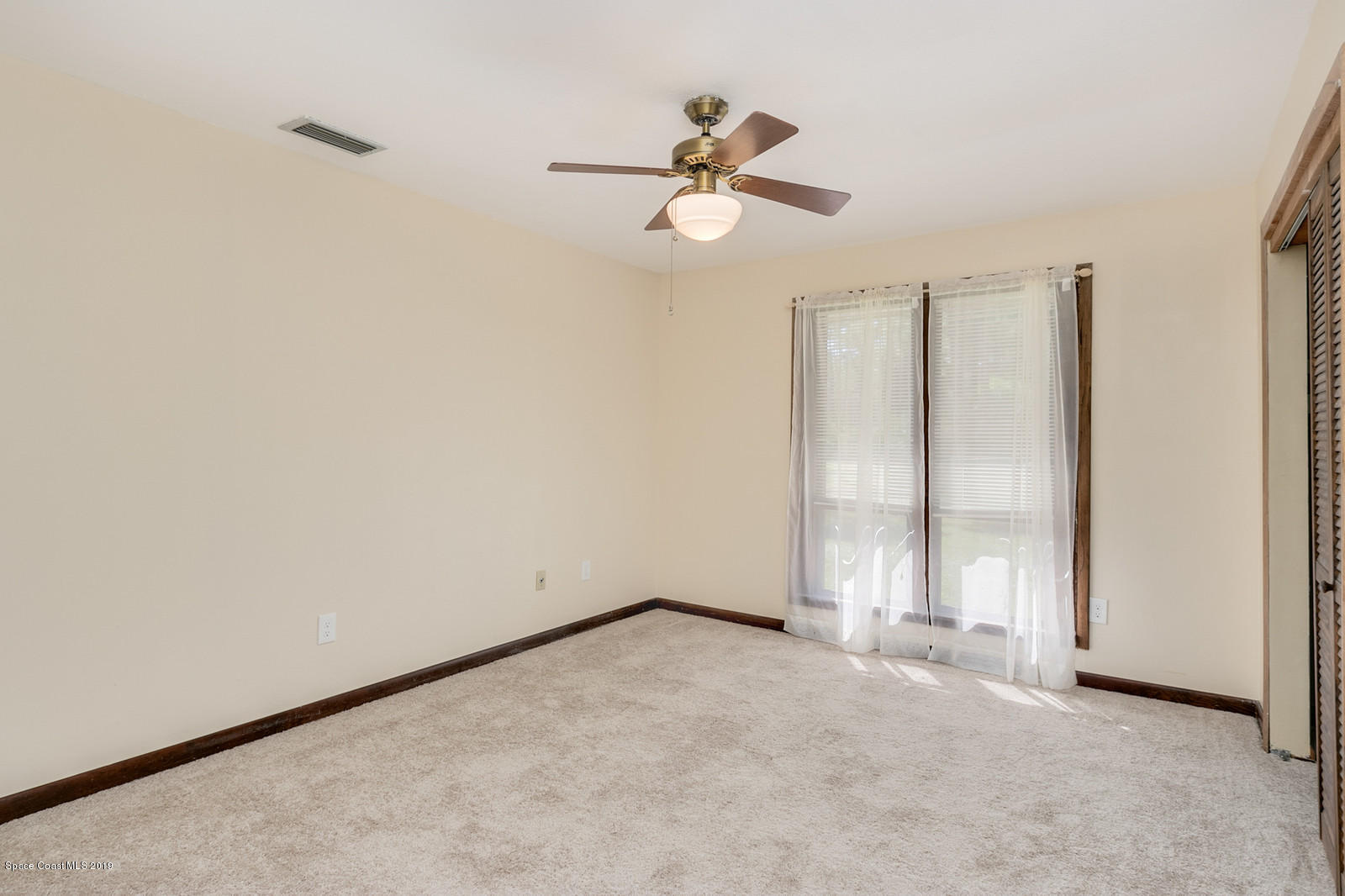 1695 Emmaus Road Northwest Palm Bay, FL 32907 - Photo 10 of 30 an empty room with a ceiling fan and carpet