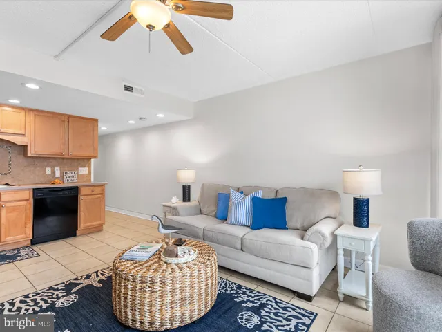 a living room with furniture a rug kitchen view and a chandelier