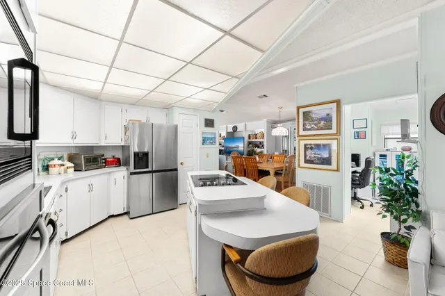 a kitchen with stainless steel appliances kitchen island granite countertop a refrigerator a stove a sink dishwasher and white cabinets with wooden floor