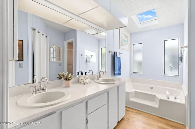 a bathroom with a sink double vanity granite tub shower and a mirror