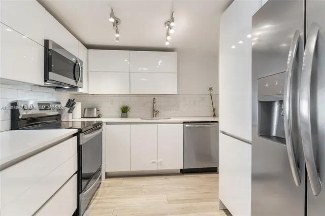 a kitchen with stainless steel appliances a refrigerator sink and microwave
