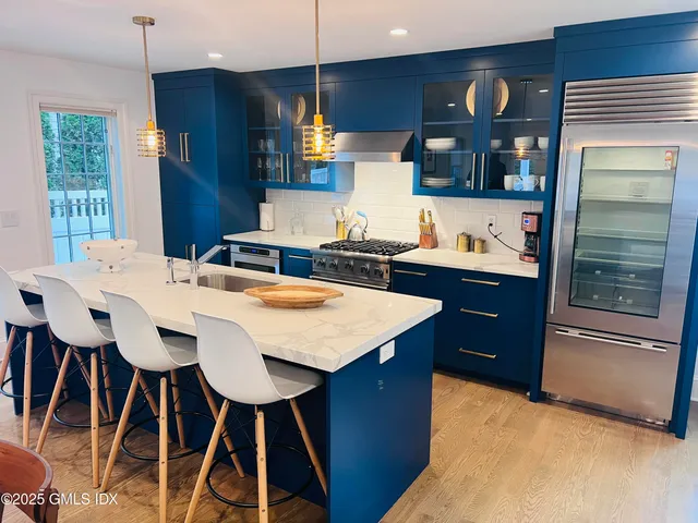 a kitchen with stainless steel appliances kitchen island granite countertop a sink a stove and chairs