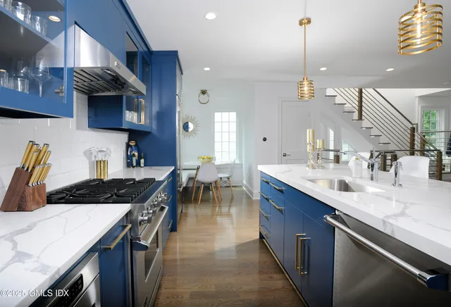 a kitchen with stainless steel appliances granite countertop a sink a stove and a wooden floors