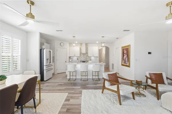 a living room with furniture and a dining table with kitchen appliances