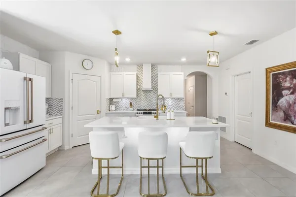 a kitchen with stainless steel appliances kitchen island granite countertop a dining table chairs and cabinets