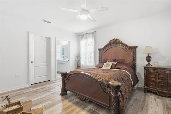 a bedroom with a bed a dresser and wooden floor