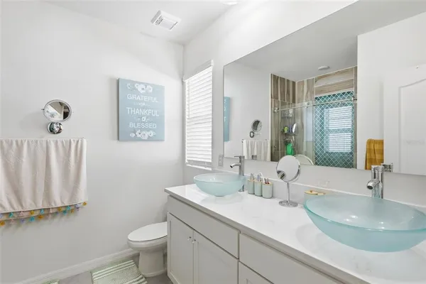 a bathroom with a double vanity sink toilet and a mirror