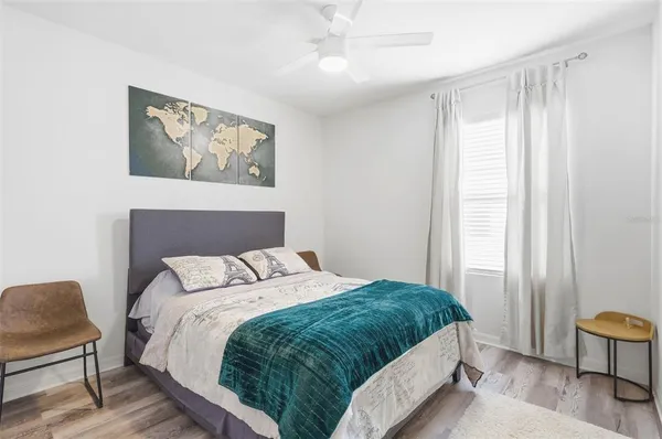 a bedroom with a bed and a chair with painting on the wall