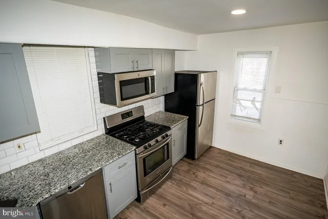 a kitchen with granite countertop cabinets stainless steel appliances and wooden floor