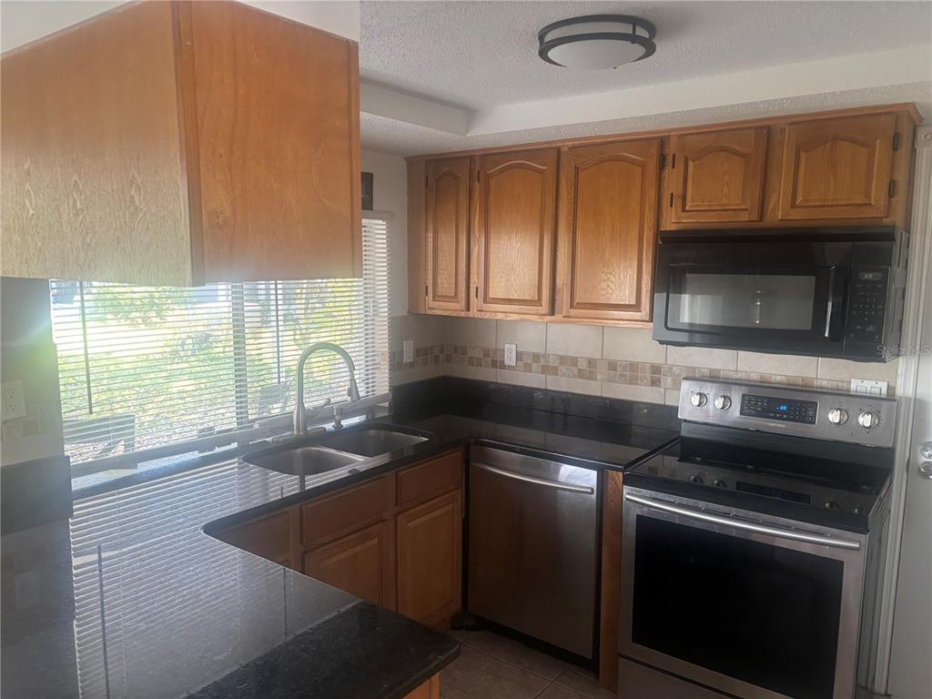 8302 Split Rail Lane Hudson, FL 34667 - Photo 4 of 21 a kitchen with granite countertop a stove a sink and a microwave