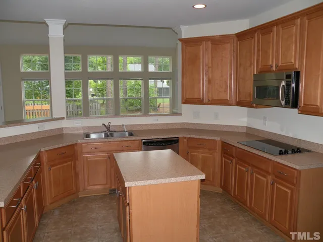 a kitchen with wooden cabinets a sink and a stove next to a window