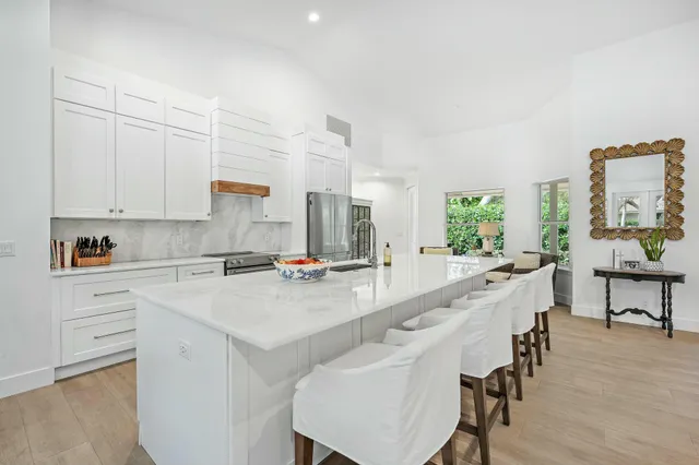 a large white kitchen with kitchen island a table and chairs in it