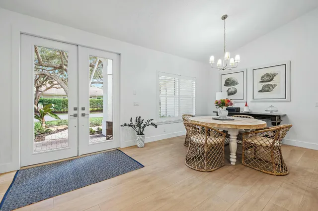 a dining room with wooden floor a chandelier a wooden table and chairs