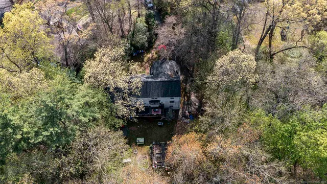 a backyard of a house with table and chairs and a large tree