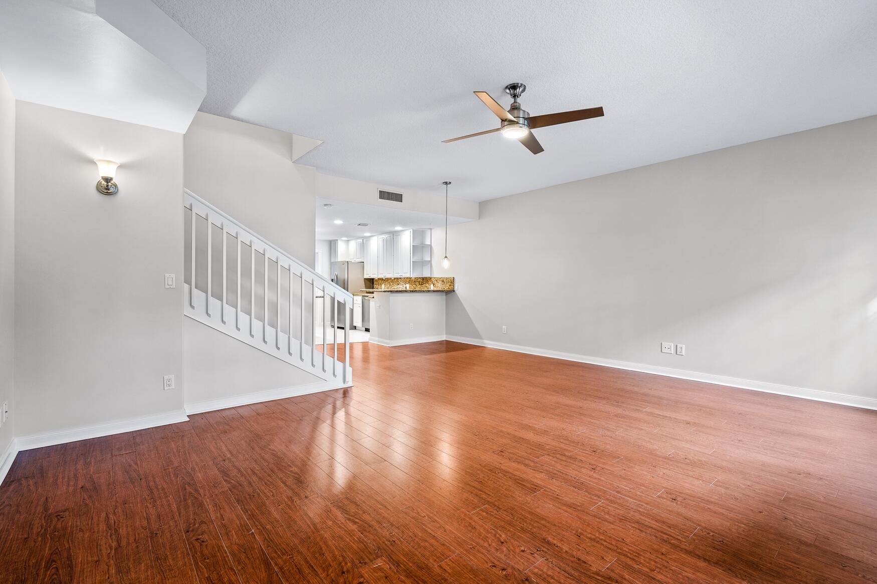 3184 West Community Drive Jupiter, FL 33458 - Photo 7 of 25 a view of a room with wooden floor a ceiling fan and windows