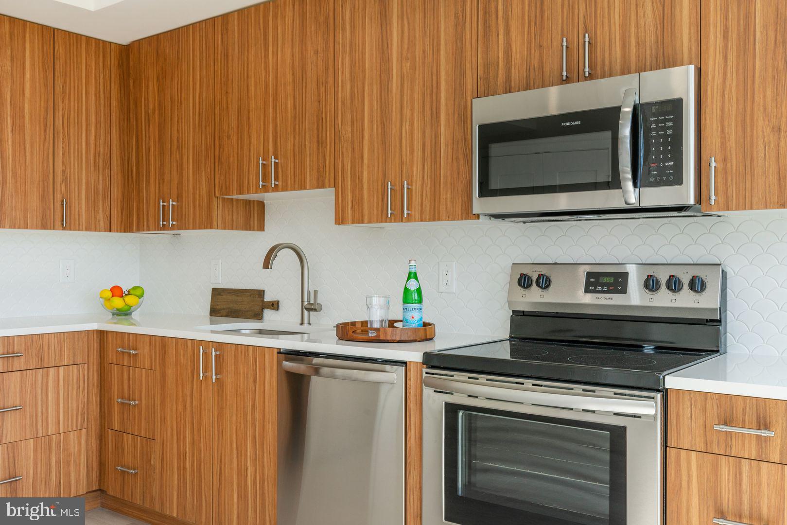 833 Wharton Street, Unit 2B405 Philadelphia, PA 19147 - Photo 4 of 15 a kitchen with stainless steel appliances a stove a microwave a sink and cabinets