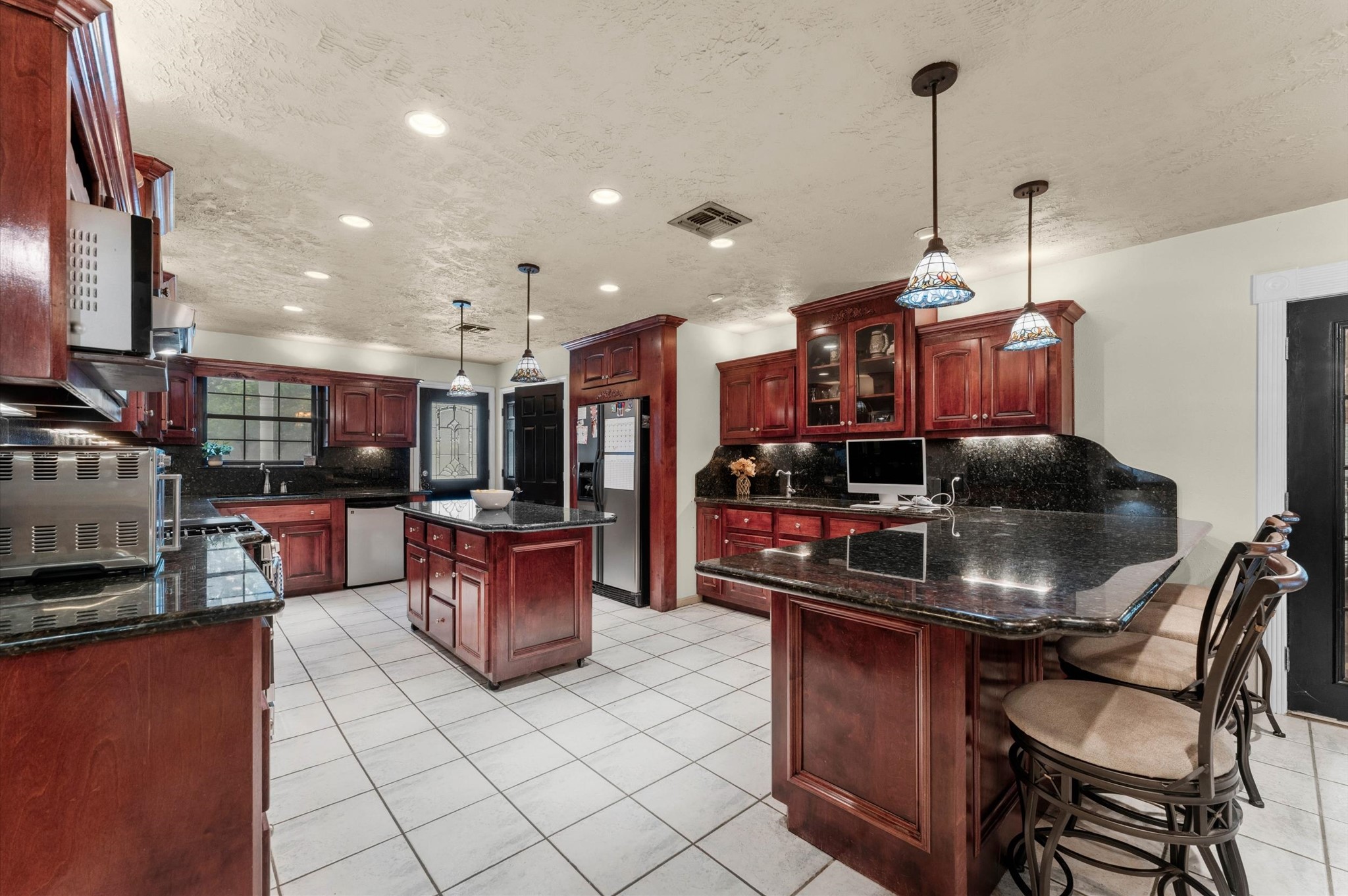 22634 Park Road Tomball, TX 77377 - Photo 11 of 29 Spacious kitchen with rich wood cabinetry and sleek granite countertops, featuring a central island and stylish pendant lighting.
