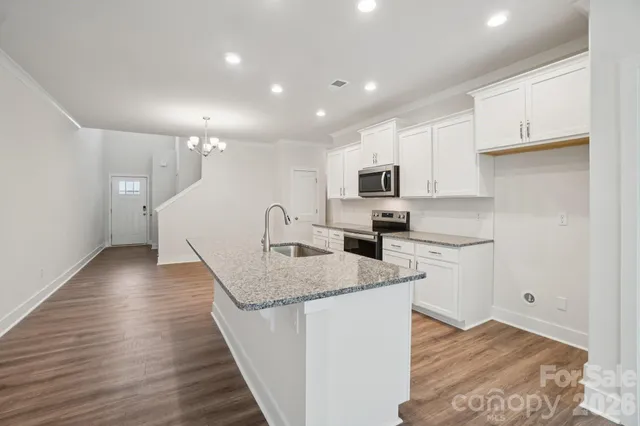 a kitchen with stainless steel appliances granite countertop a sink a stove top oven a counter space and cabinets