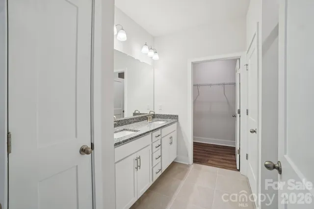 a bathroom with a granite countertop sink two mirror and a shower
