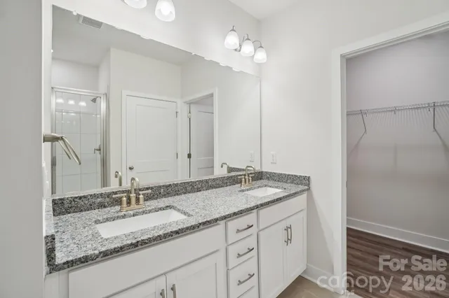a bathroom with a granite countertop double vanity sink and a mirror