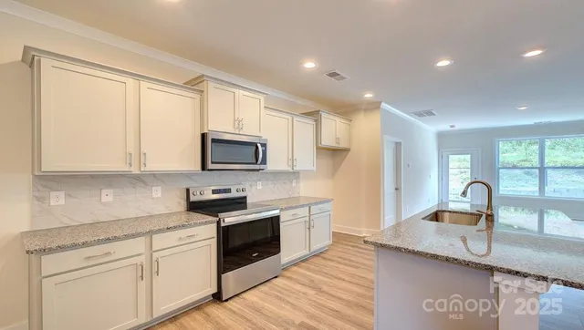 a kitchen with granite countertop a sink stainless steel appliances and white cabinets