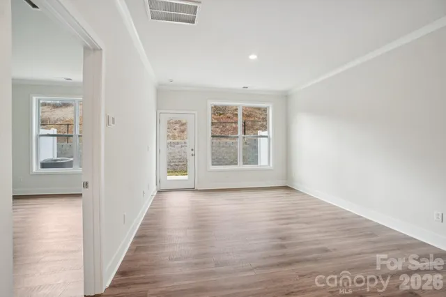 a view of an empty room with wooden floor and a window