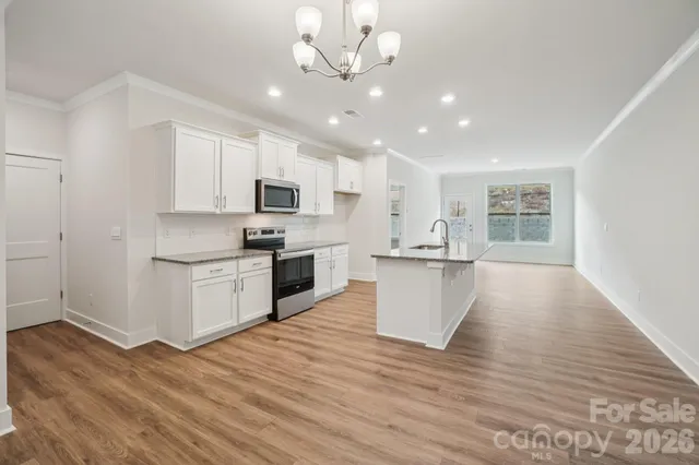 a view of kitchen with granite countertop stove top oven and cabinets