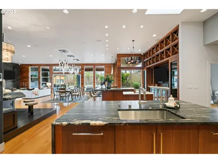 a open kitchen with stainless steel appliances granite countertop a refrigerator a sink dishwasher a dining table and chairs with wooden floor