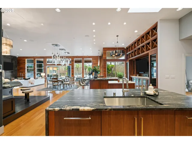 a open kitchen with stainless steel appliances granite countertop a refrigerator a sink dishwasher a dining table and chairs with wooden floor