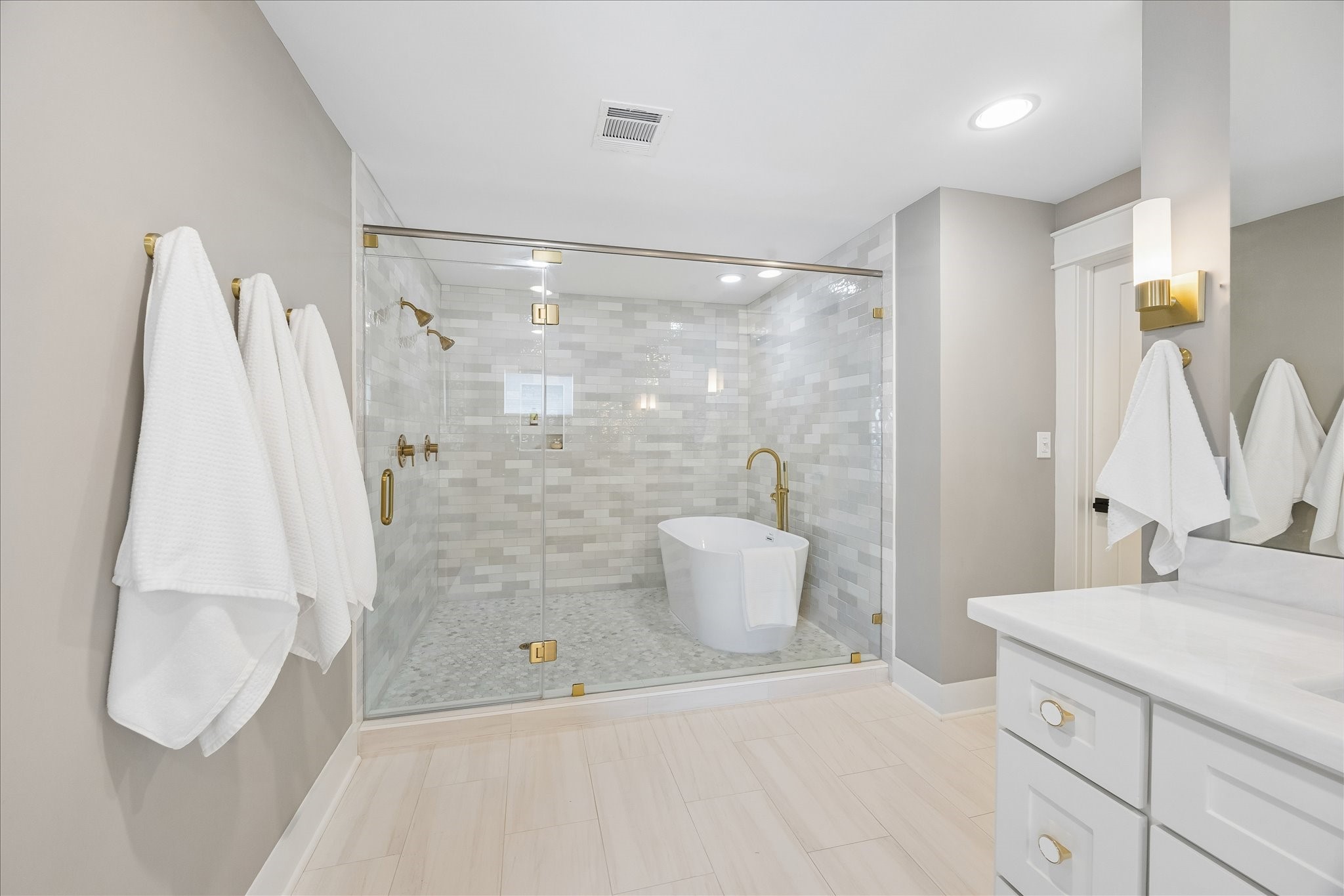 1112 Merrill Street Houston, TX 77009 - Photo 2 of 42 The en-suite primary bath feels like a private spa. It includes double sinks, a huge frameless walk-in shower, and a beautiful separate soaking tub enclosed in glass. It’s the perfect place to relax at the end of the day.