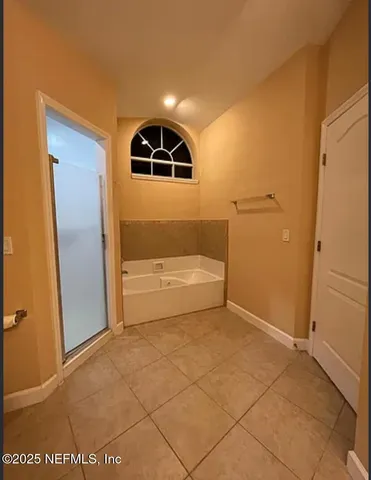 an empty room with chandelier fan and windows