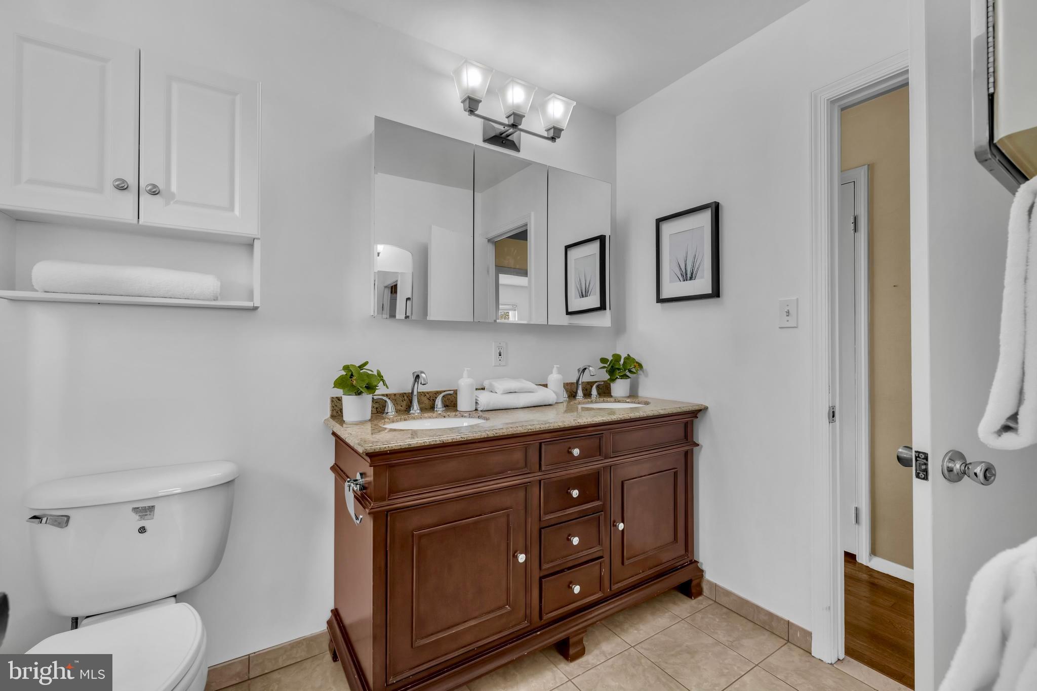 9807 Locust Avenue Lanham, MD 20706 - Photo 23 of 59 a bathroom with a granite countertop toilet sink and mirror