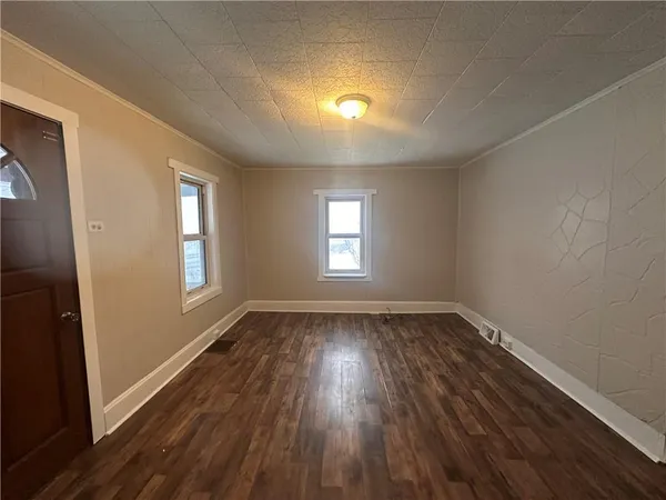 a view of an empty room with wooden floor and window