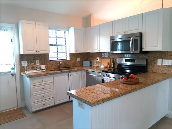 a kitchen with stainless steel appliances granite countertop a sink dishwasher stove and oven with white cabinets