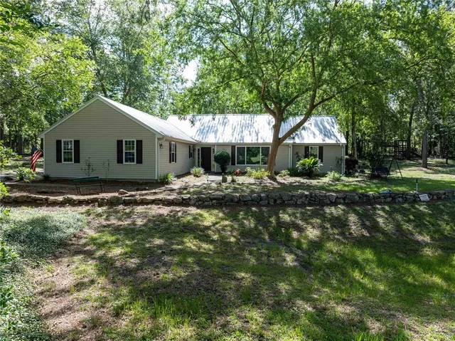 a backyard of a house with large trees and outdoor seating