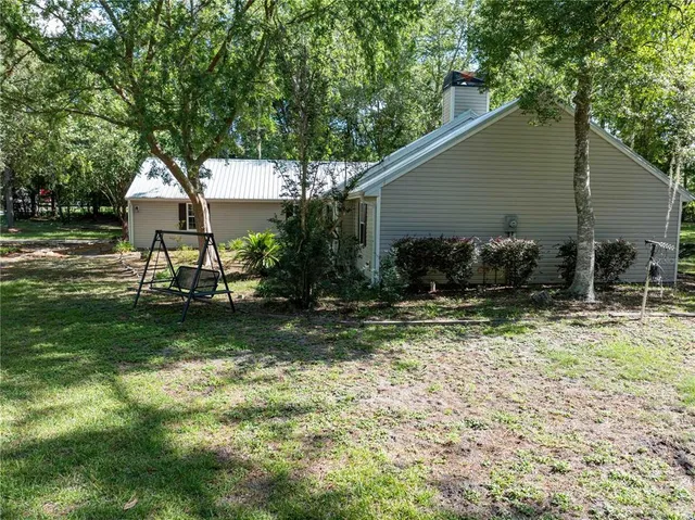 a backyard of a house with table and chairs under an umbrella