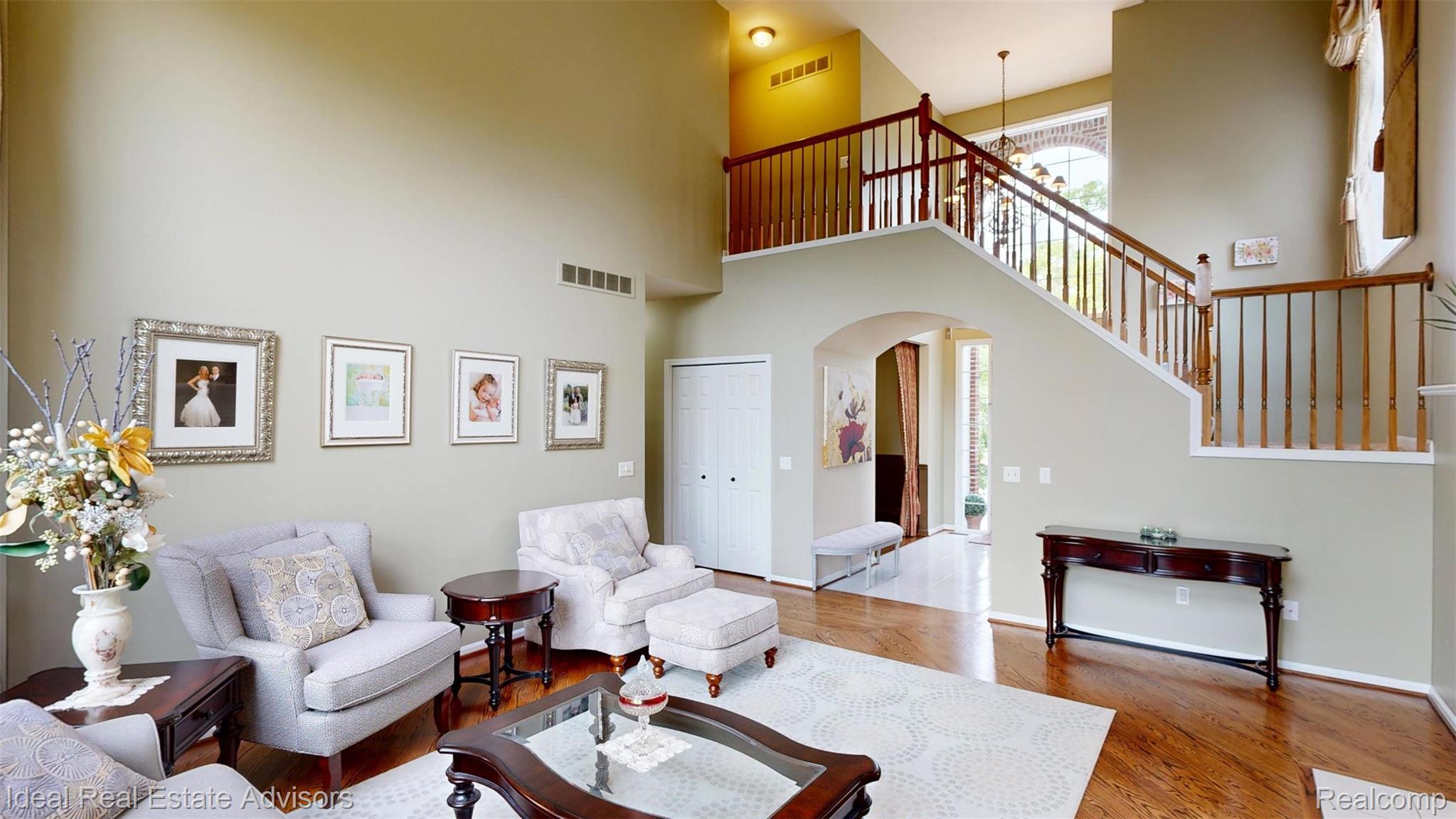 1364 Kentfield Drive Rochester, MI 48307 - Photo 23 of 70 Two-story living area featuring wood-finish flooring, a grand staircase with wood railings, a second-story overlook, and an arched entryway