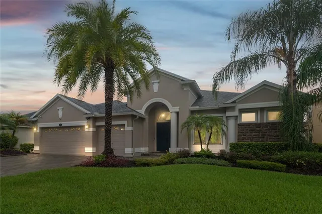 a front view of a house with a garden and palm trees