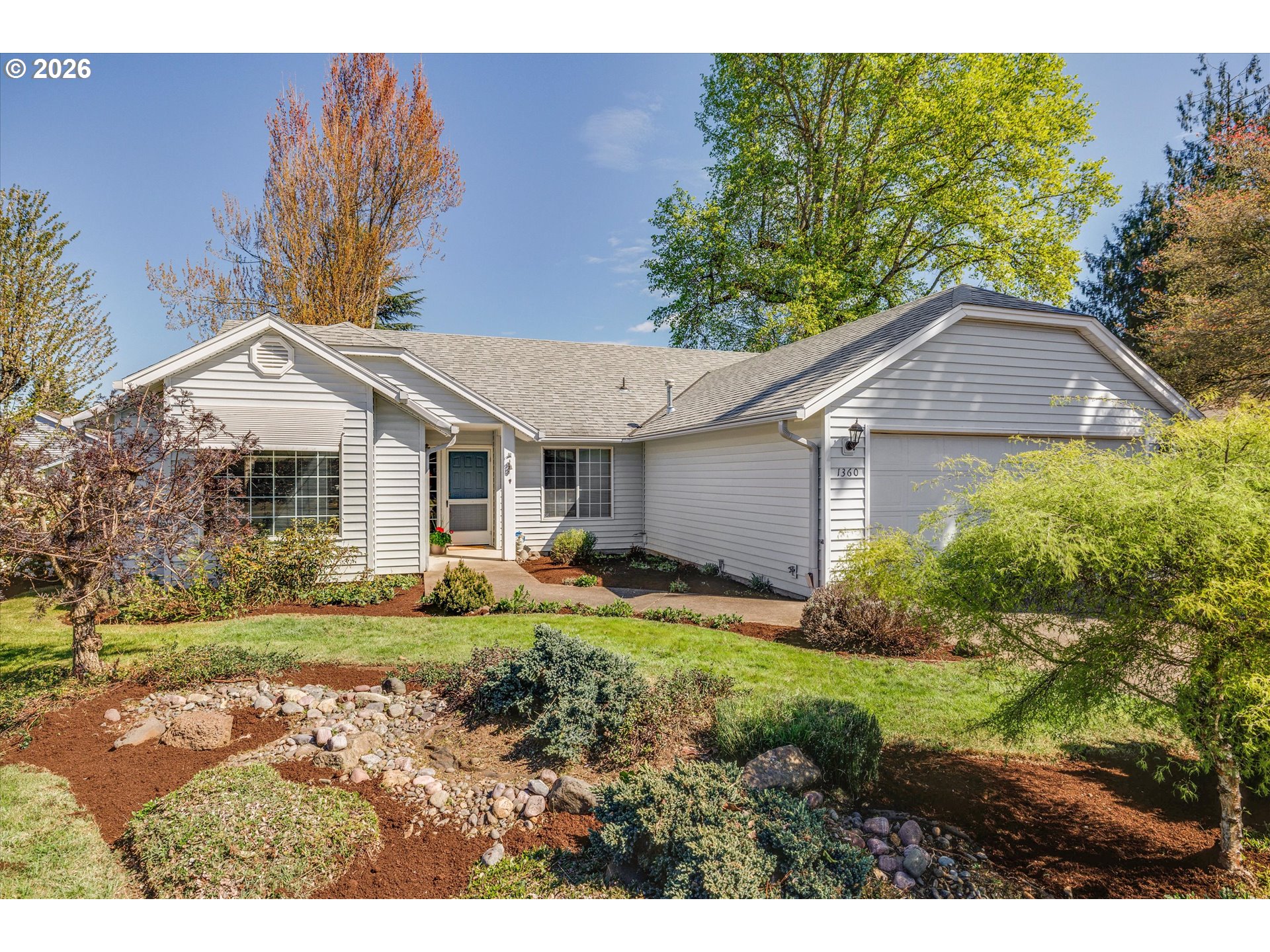 1360 North Locust Street Canby, OR 97013 - Photo 2 of 36 a view of a yard in front of a house with plants and large tree