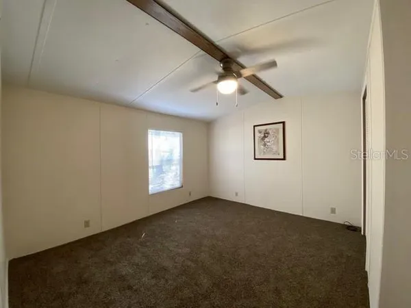 an empty room with a window and a fan