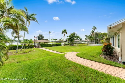 a view of a house with a yard and large tree