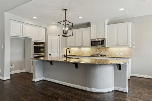 a kitchen with kitchen island granite countertop a sink cabinets and stainless steel appliances