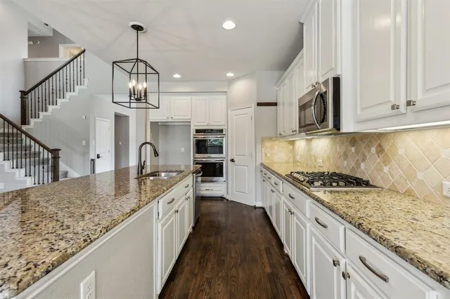 a kitchen with stainless steel appliances granite countertop a sink stove and cabinets