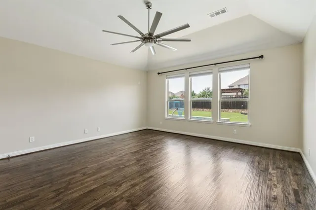 a view of an empty room with wooden floor and a window