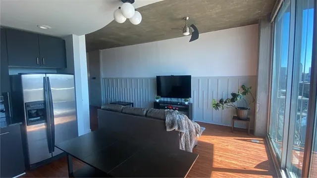 a living room with furniture a flat screen tv and a refrigerator